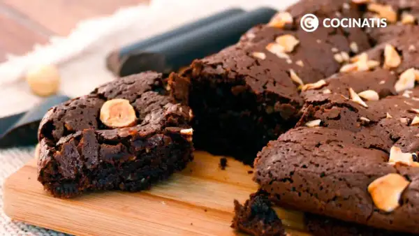 Delicioso brownie sin gluten, con trozos de avellana, sobre una tabla de madera.