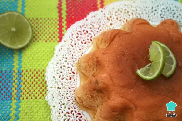 Delicioso flan de limón con rodajas de lima, servido sobre un mantel colorido y un encaje blanco.
