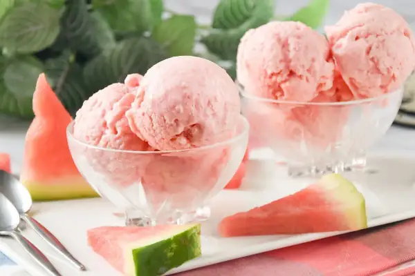 Dos copas de cremoso helado de sandía, decoradas con trozos de fruta fresca. ¡Un postre refrescante!