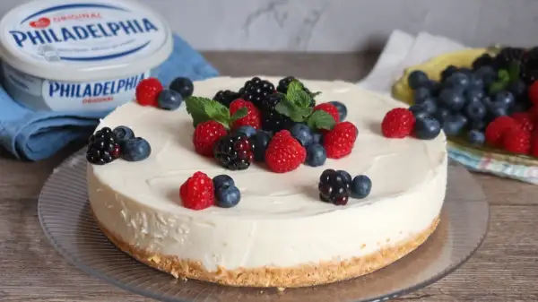 Deliciosa tarta de queso fría cubierta con frambuesas, moras y arándanos frescos. Un postre perfecto para cualquier ocasión.