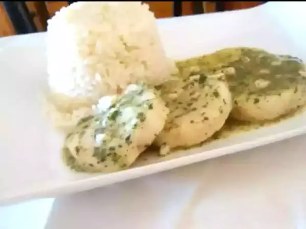 Merluza en salsa verde, un plato delicioso con pescado blanco bañado en una sabrosa salsa de perejil y ajo, acompañado de arroz blanco.