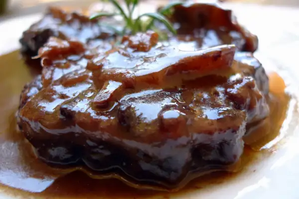 Rabo de ternera estofado, jugoso y tierno, bañado en su propia salsa oscura y aromática, con un toque de romero fresco.