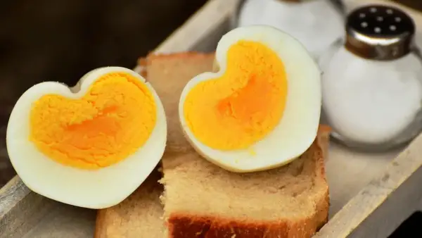 Dos mitades de huevo cocido, con forma de corazón, sobre tostadas. Ideal para saber cuanto tarda en cocer un huevo y disfrutar de un desayuno.
