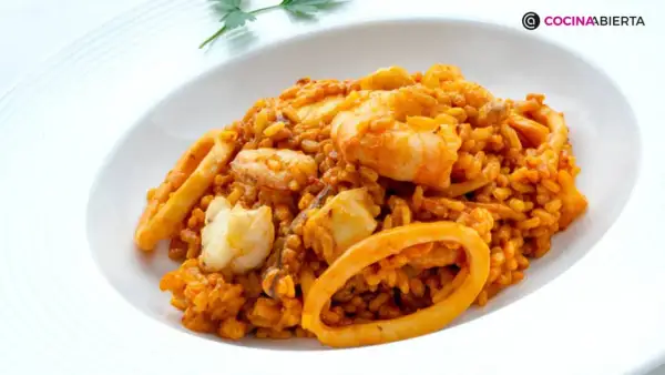 Arroz del senyoret con gambas, calamares y trozos de pescado blanco, servido en un plato blanco.