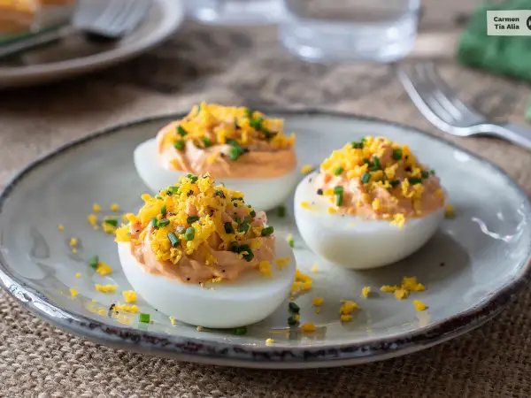 Huevos rellenos de atún, decorados con ralladura de huevo y cebollino. Un aperitivo delicioso y fácil de preparar.