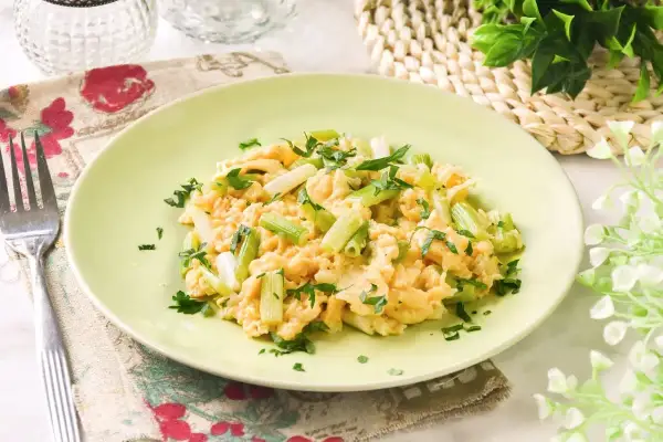 Revuelto de ajetes con perejil fresco, servido en un plato verde claro. Un desayuno ligero y sabroso.