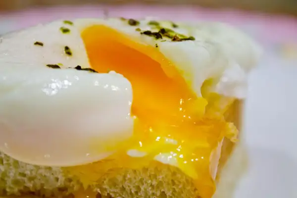Un huevo poche microondas perfecto, con la clara cuajada y la yema líquida, servido sobre una tostada.